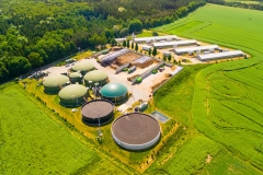 Aerial view over biogas plant and farm in green fields. Renewable energy from biomass. Modern agriculture in Czech Republic and European Union.